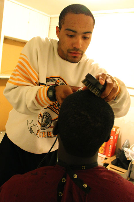 WSU Senior Nichio Bryant cuts hair in a client’s home as part of his door-to-door business plan, Tuesday, Sept. 17, 2013. Bryant inherited his clippers from his grandfather.