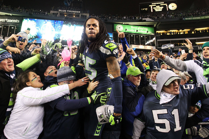 Seattle cornerback Richard Sherman climbs into the crowd while celebrating the Seahawks’ NFC Championship victory at CenturyLink Field in Seattle, Sunday, Jan. 19.