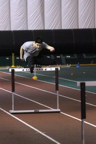Freshmen Daniel Zmuda leaps over a hurdle during a track practice in the Indoor Facility, Wednesday, Feb. 12.