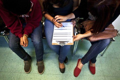 A Roosevelt High School student is helped by her friends while filling out a form about her sexual history and habits to gain reproductive services at the school’s clinic in Los Angeles, May 28, 2012.