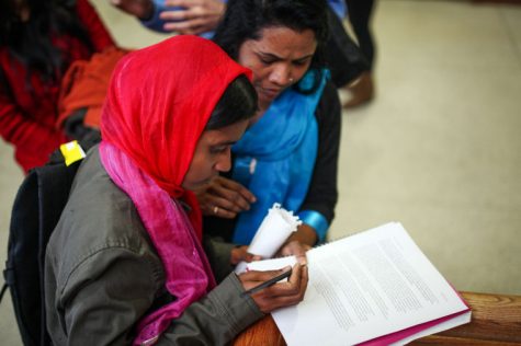 Aleya Akter (right), and Aklima Kahanam (left), sign a letter regarding sweatshops and working conditions in Bangladesh, Monday, April 1.