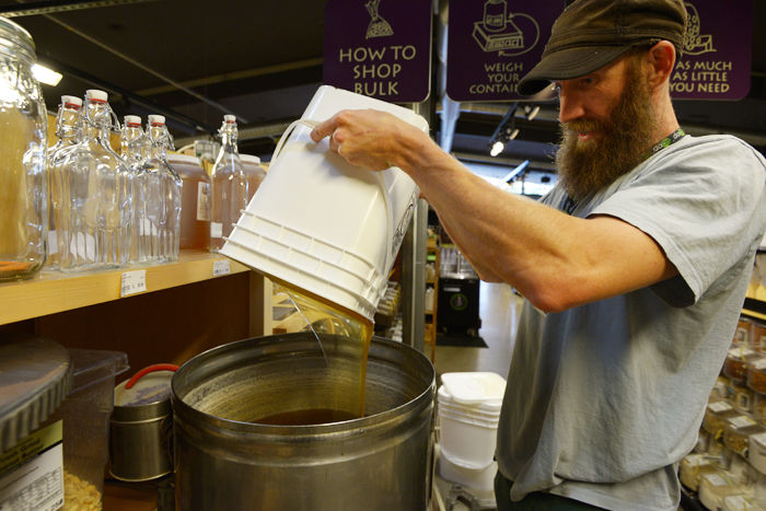 Matthew McConnell, who works in the bulk section of the Moscow Food Co-op and has been an owner since the day he moved here a year ago, refills a vat of honey produced locally in Moscow.