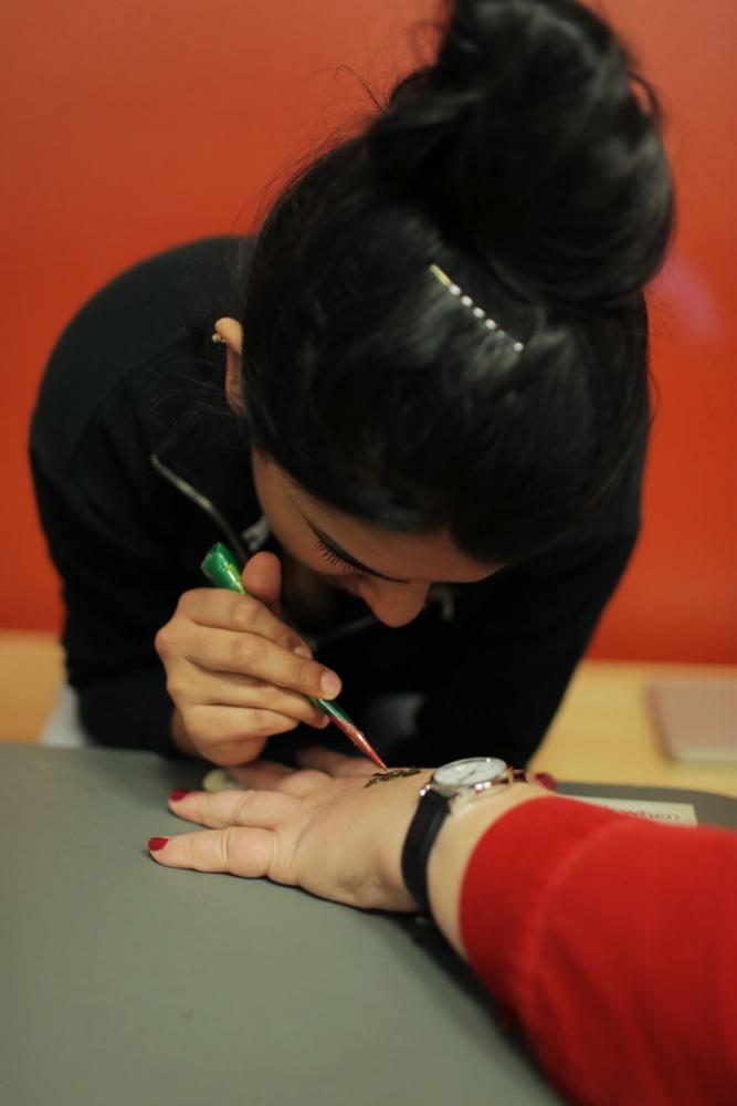 Ramneet Kaur, a member of the Sihk Student Association, applies henna to Karen Weatherman in the CUB on Tuesday.