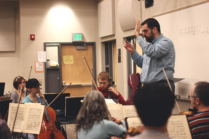 Conductor Jeremy Briggs Roberts leads the orchestra in the Pullman High School band room.