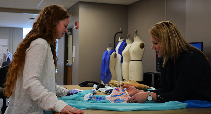 Apparel, Merchandising, Design and Textiles senior Davis Scilley, left, looks over her designs for a sheath dress with assistant professor Debbie Christel on Tuesday.