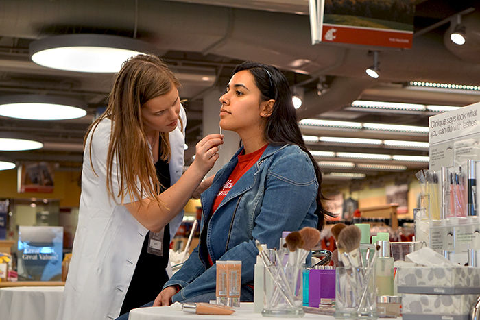 A member of the Clinique staff at The Bookie demonstrates a makeover on a patron. Clinique offers a mother-daughter makeover during Mom’s Weekend.