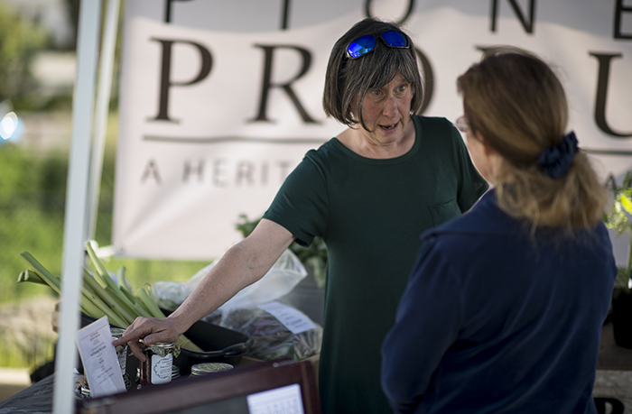 Peggy Welsh from Pioneer Produce helps a customer at the Pullman Farmers Market on May 10.