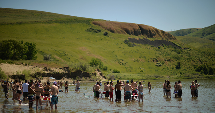 Dozens of people socializing and playing beer pong at the Illia Dunes on Monday. The shallow water and sandy beach is located about 50 miles away from WSU, making the dunes a popular local get-away.