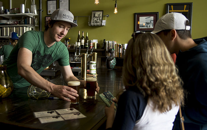 Co-owner of Moscow Brewing Company Aaron Hart serves beer to customers June 17 at their grand reopening.