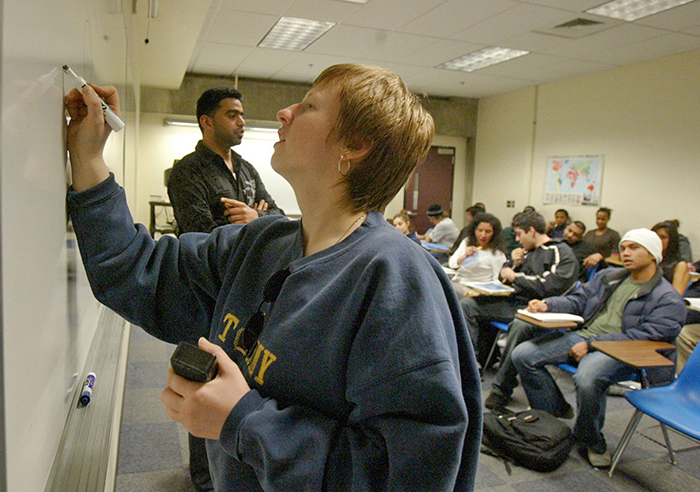 Student Diane Haugsvar, foreground, draws on the board during Fahad al-Balushi’s Arabic class at Bellevue Community College in Bellevue, Washington.