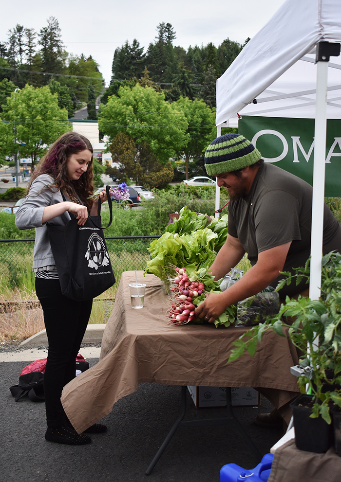 Jason Parsley, right, sells radishes to a customer Wednesday at the Pullman Farmer's Market.