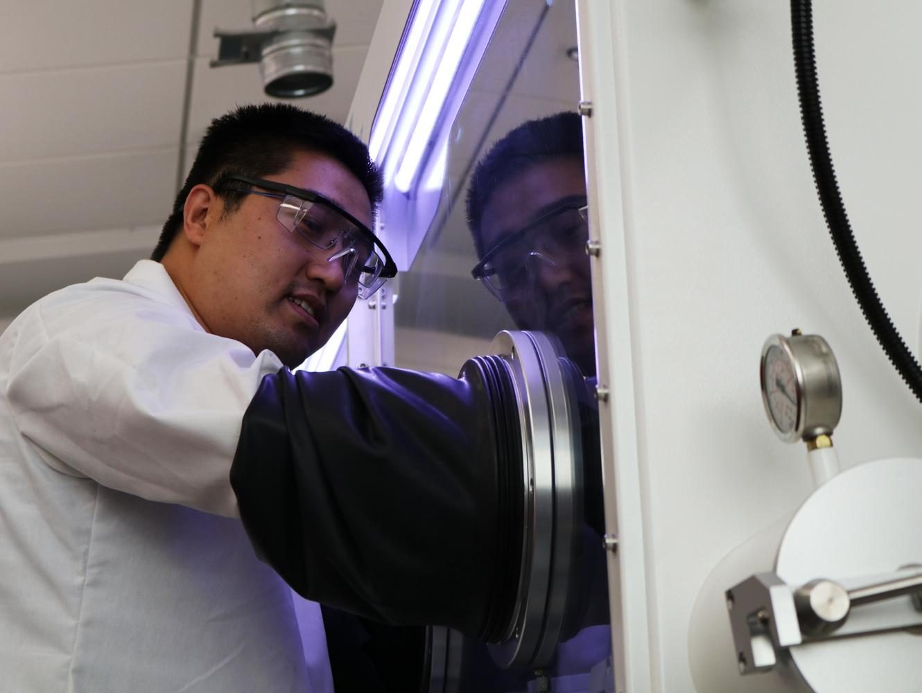Qiang Zhang demonstrates how a glove box works Thursday in Troy Hall on Thursday.