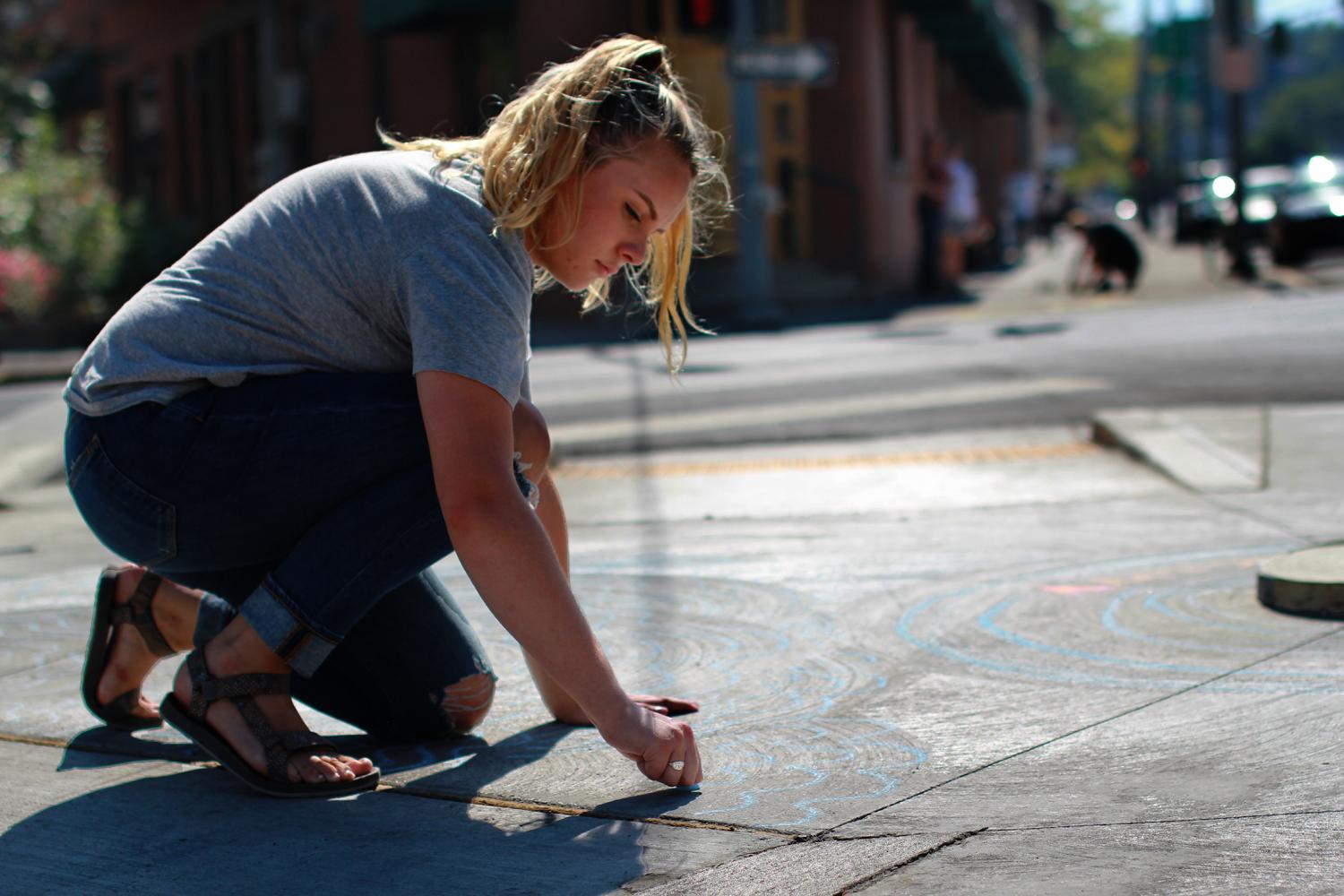 WSU Landscape Architecture student Addy Martoncik draws water designs Thursday afternoon along Grand Avenue.  The students made a chalk illustration to raise awareness of the river many Pullman 
residents are unaware of as part of the Landscape achitecture sophmore studio.  
