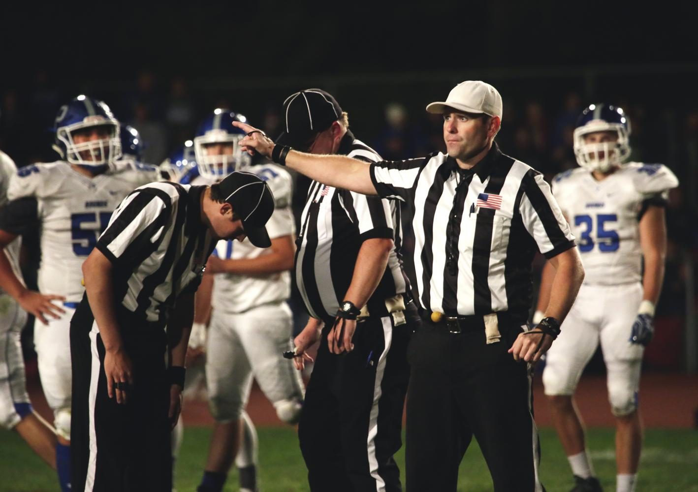 Referees come together for a flag in a game between the Pullman Greyhounds and Moscow Bears at Moscow High School on Friday.