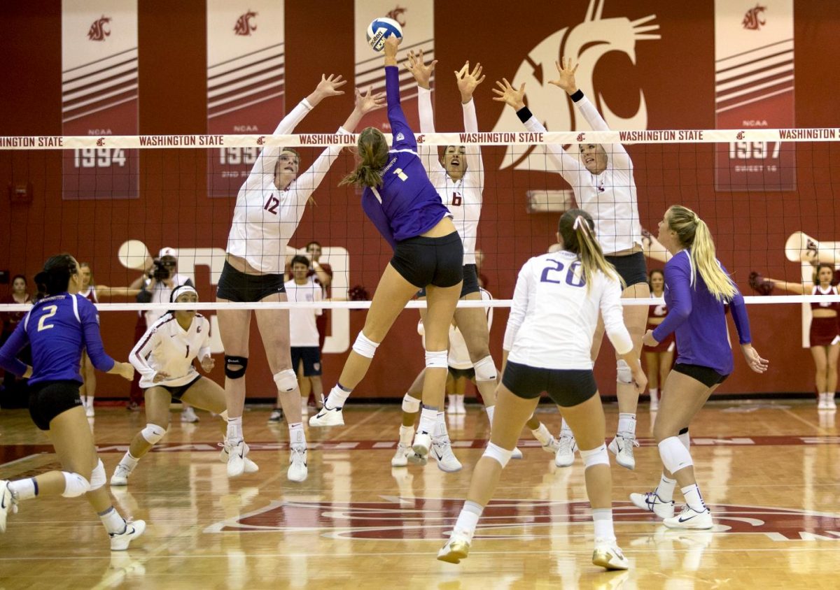 Cougar volleyball players leap to block a spike from Husky freshman middle blocker Lauren Sanders on Sept. 20.