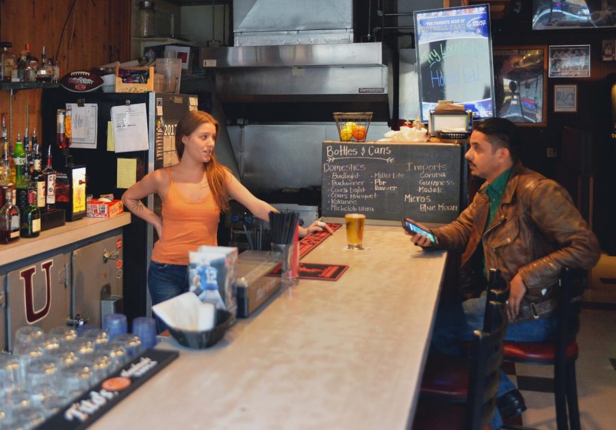 Mary Tucci, a bartender at The Sports Page bar, talks to customer Jon Hawley during a slow shift Tuesday evening.