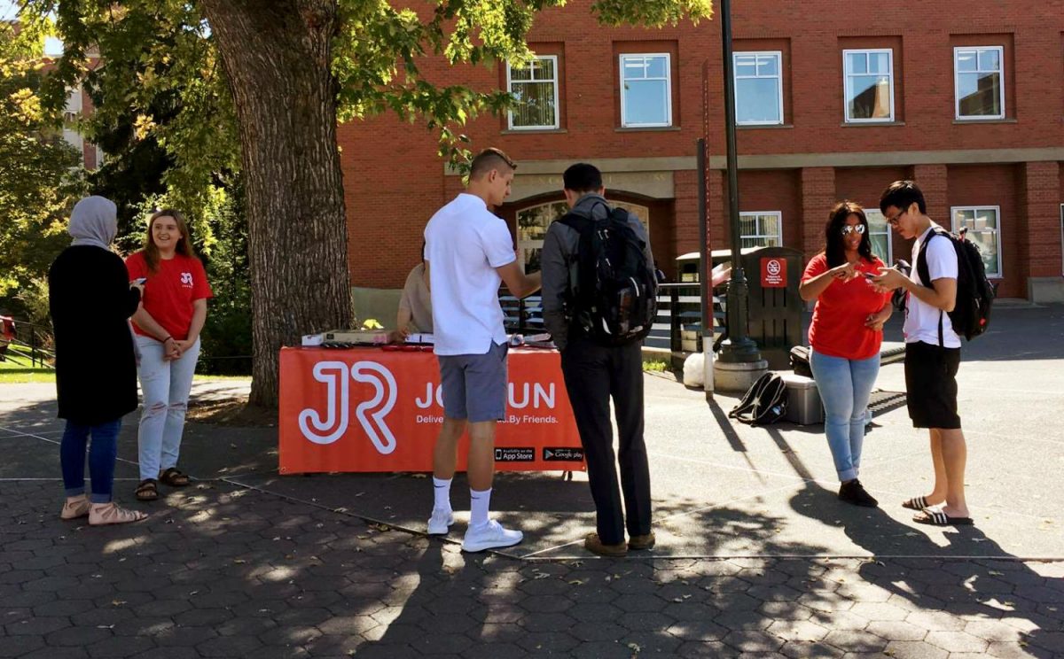 Student interns speak with people passing by on the Glenn Terrell Friendship Mall, offering free food, such as pizza and donuts, to those who sign up on the app.