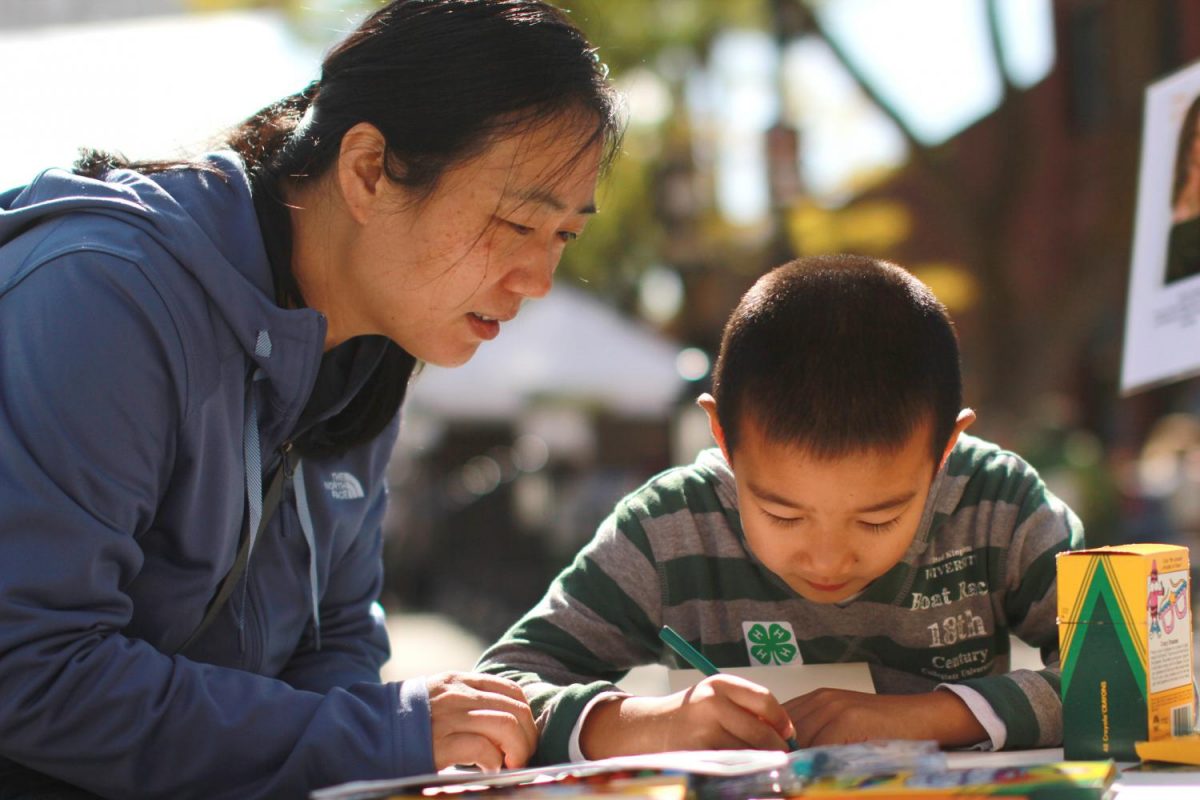 Hui Li and her seven-year-old son Jim Liu write welcome letters to refugees Saturday. The cards will be sent to refugee centers in Boise and Twin Falls, Idaho.