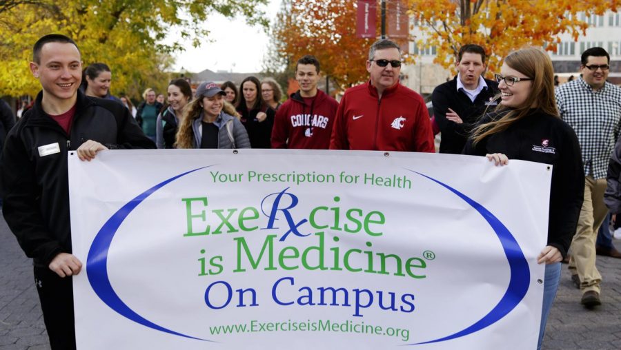 WSU president Kirk Schulz marches with students and faculty for the all-campus walk Monday.  In front, students Michael Shiftlet (left) and Ariel Bowman carry the exercise is medicine banner.