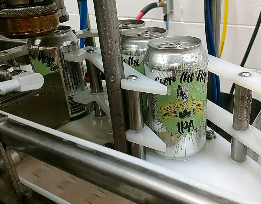 The popular Over The Hop IPA beer goes through the canning machine. 
Canned beer is sold in six-packs for $9.99.