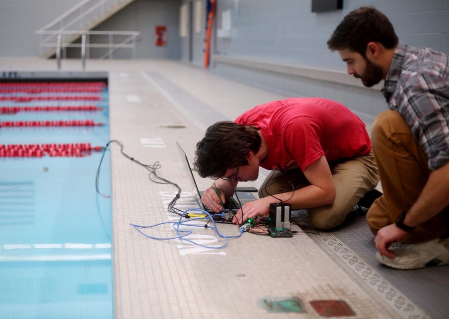 RoboSub Club treasurer Ryan Summers and club member James Irwin fine tune the circuit board for the hydrophones for their robotic submarine at Gibb Pool. The submarine detects soundwaves to follow underwater.