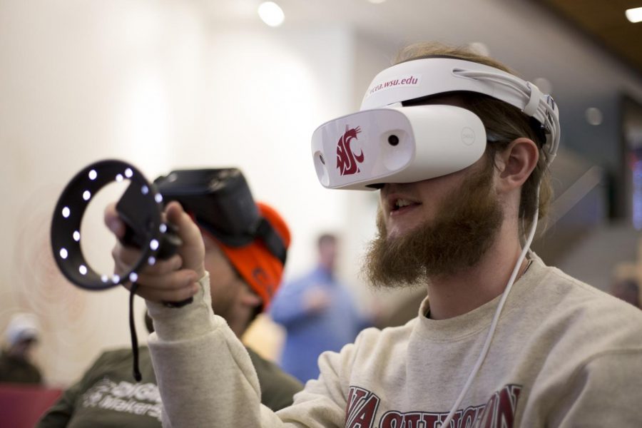 Garth Bates, a junior computer science major, learns VR controls while using a VR headset and a hand controller at the Olympic Games Highlight VR event Wednesday in the Voiland College of Engineering and Architecture.