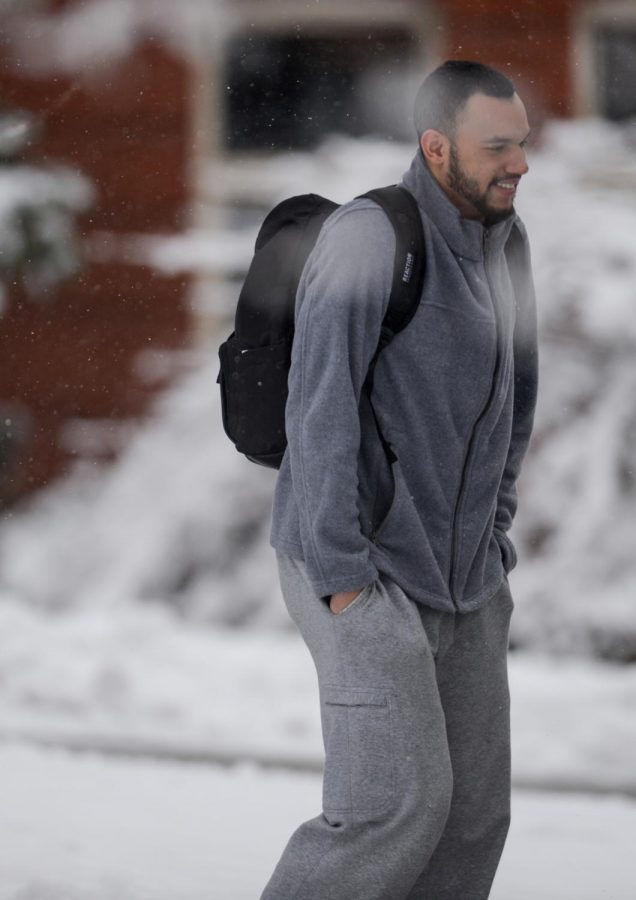 Cordae Mcafee gets showered with snow while walking past Murrow Hall.