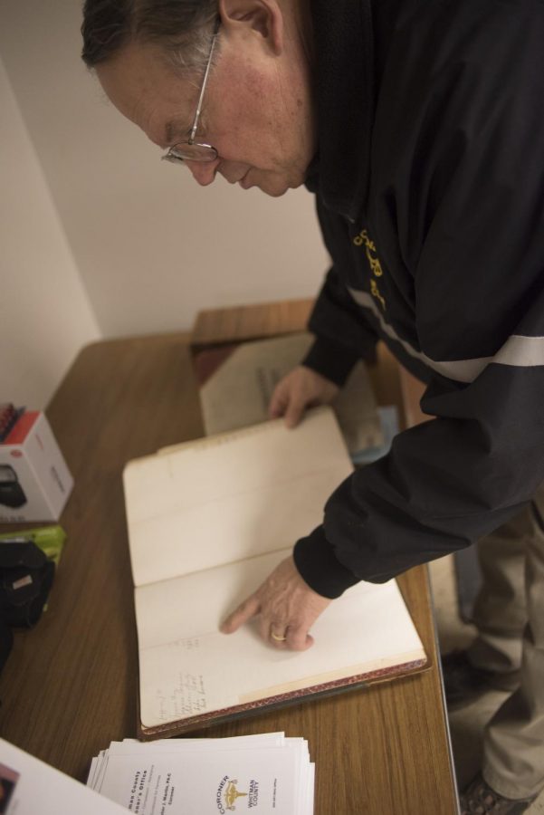 Martin flips through an old Whitman county coroners filing book dating back to the 1900s in his office Wednesday in Colfax.