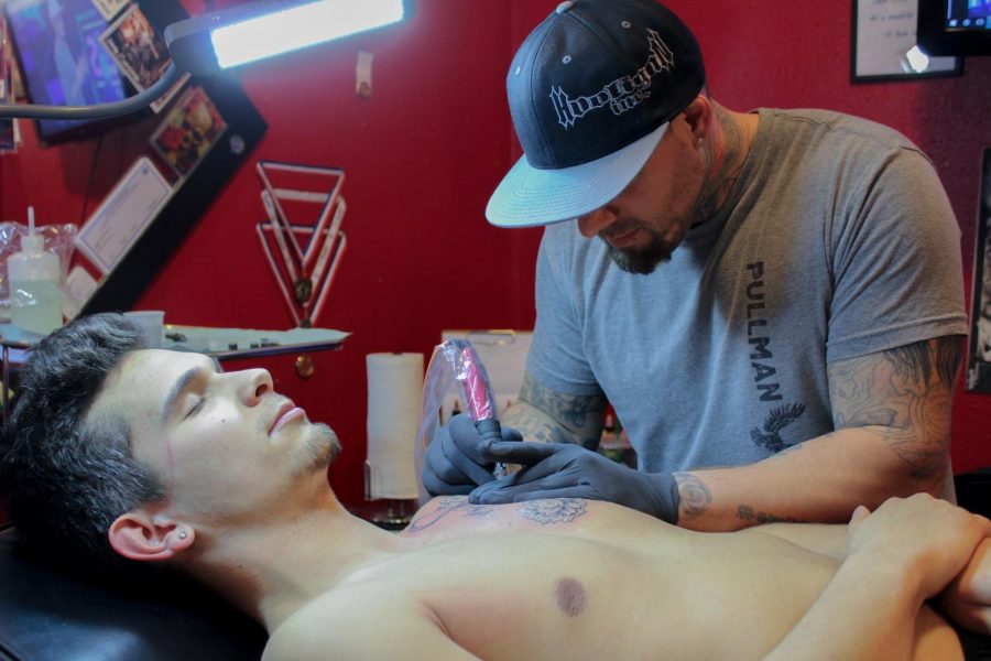 Blood Diamond Ink owner Chris Peltier gives WSU junior Cory Salander a chest tattoo. Triumphant Tattoo artist Todd Holley said wearing gloves is more for the protection of artists than it is for the customers. 