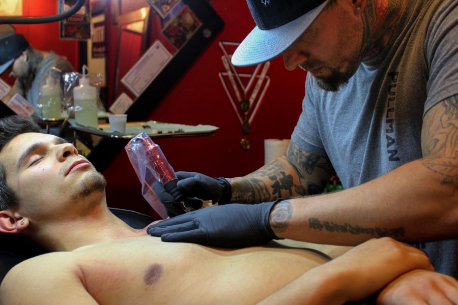Cory+Salander%2C+a+junior+at+WSU%2C+receives+a+chest+tattoo+from+Blood+Diamond+Ink+owner+Chris+Peltier.+