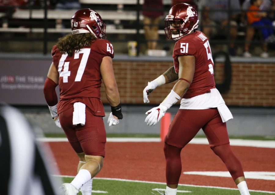 Senior and former linebacker Frankie Luvu, right, celebrates a play for the Cougs in 2018.