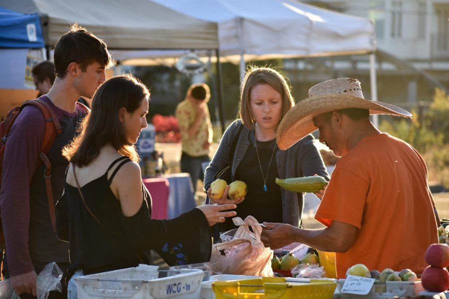 Rafael Aviña helps customers at the Pullman farmer’s market. Healthier, local foods could benefit students.