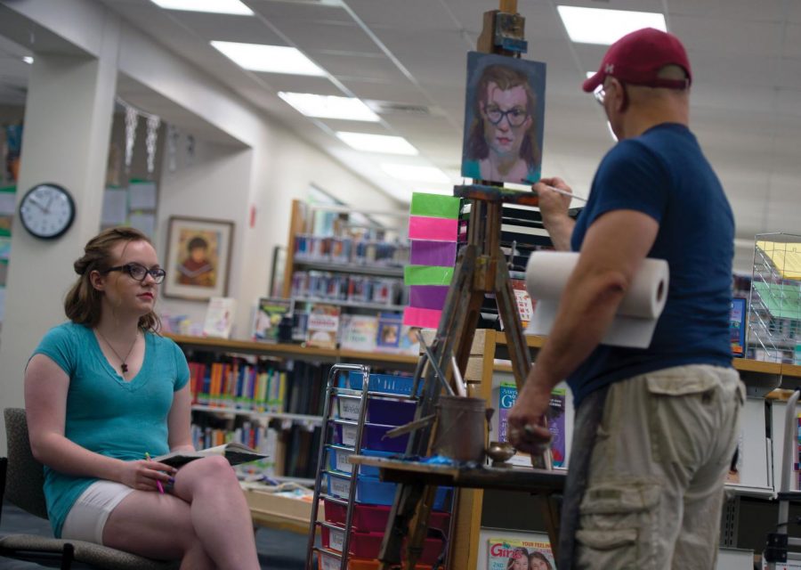 Henry Stinson, an art teacher at Colfax High School, does a live portrait painting of reporter Chloe Grundmeier as she takes notes at Neill Public Library during the Pullman Artwalk on May 19.