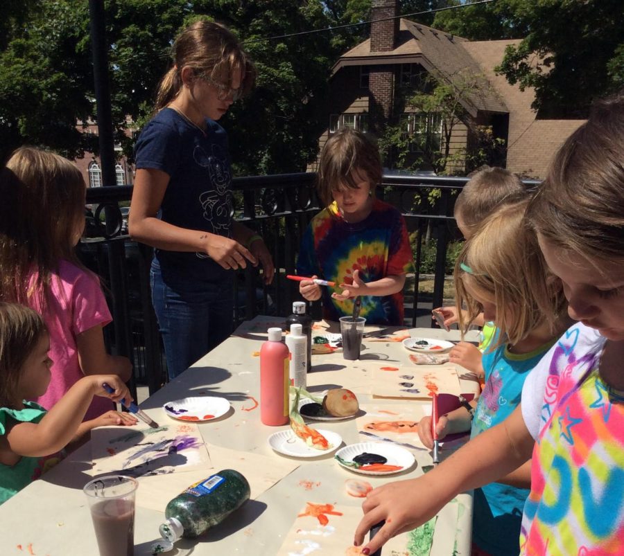 Children dab brushes on their hands to try out finger painting during a Summer Reading Program event last summer.