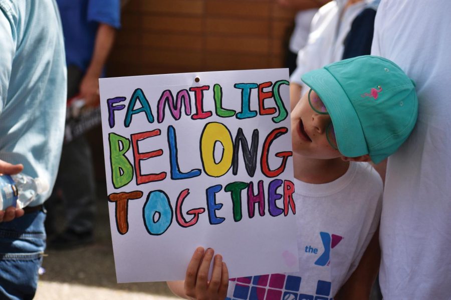 Vivian Ellsworth, 9, stands next to her father Noel, 43, and holds a sign protesting the separation of families at the U.S.-Mexico border during a rally in Pullman on Saturday.