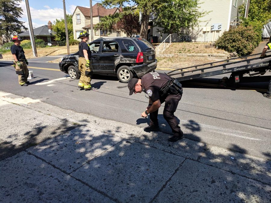 Ruben Harris, a Pullman PD officer, cleans up debris from a car crash near the intersection of Whitman and Kamiaken streets Friday.