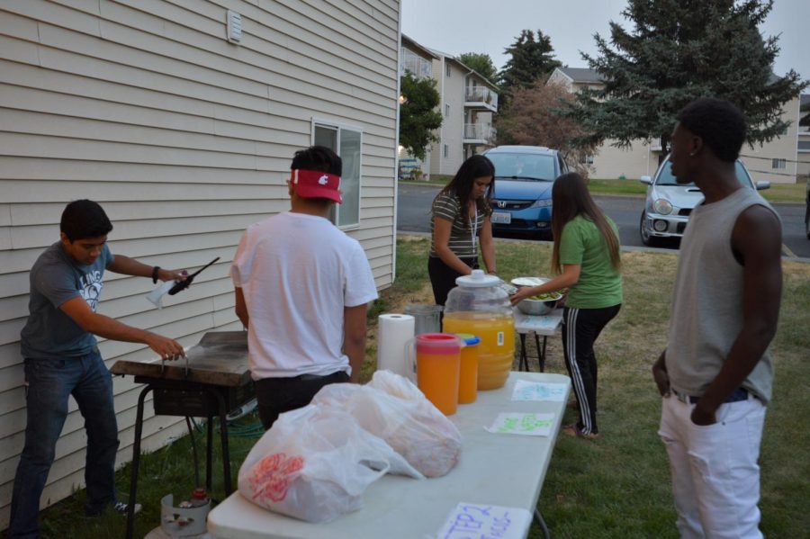 Members of the Crimson Group prepare the taco stations as Jesus Policarpo preps the grill Thursday night for the Taco Sale Emergency fundraiser.