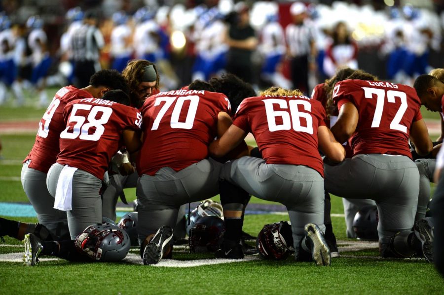 The offensive line and members of the WSU football team kneel after running out of the tunnel right before the coin toss Saturday night against San Jose State at Martin Stadium.