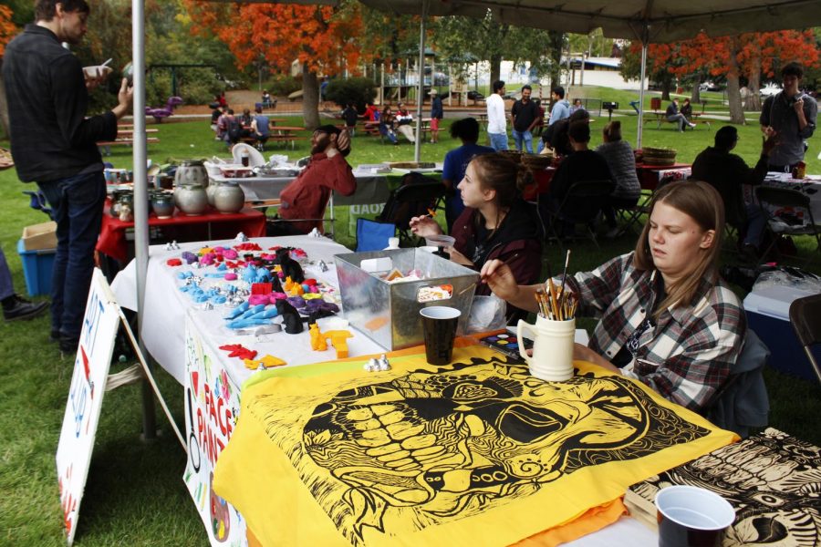 Art Club members Kira Walters and Sidney Westenskow advertise 3D-printed art projects and hand-carved tapes¬tries from art students during the International Students’ Council ‘Party in the Park’ on Saturday at Reaney Park.