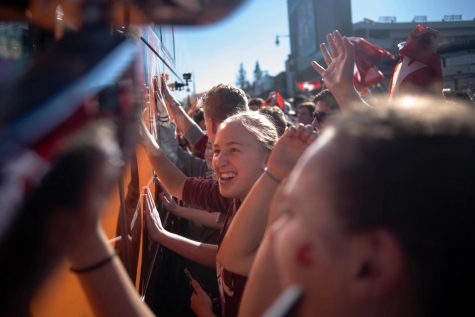 Students run to touch the College GameDay bus while chanting and jumping Wednesday on Stadium Way.