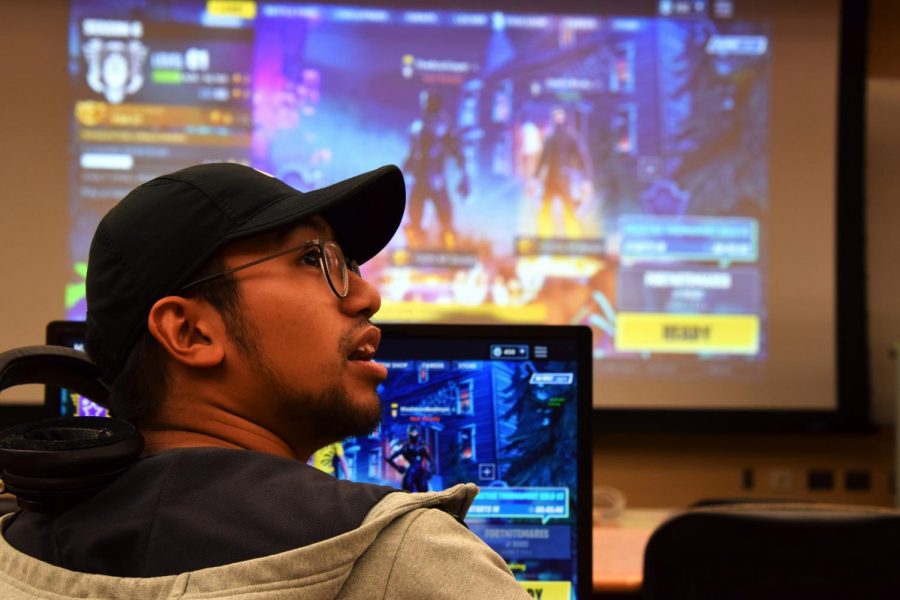 Senior computer science major Teej Cortez takes a breather in between matches of Fortnite as the Twitch stream of the event plays in the background at the esports competition Sunday in CUE.