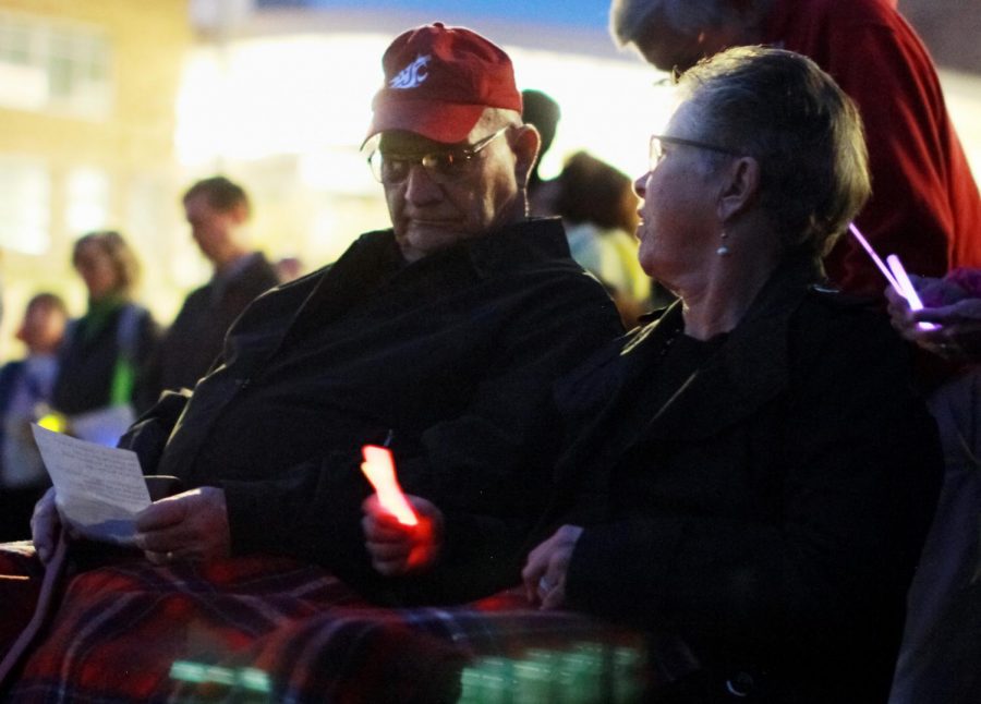 Lauren McCluskey’s grandparents, Ross and Joyce Rudeen, pass glowsticks that replaced candles at their granddaughter’s vigil Wednesday night at the Pullman High School track.
