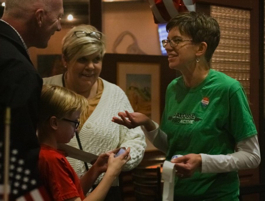 Julie Kmec, member of the Palouse Proactive leadership team, greets and hands out voting stickers to guests during the organizations I Voted party on Tuesday night at South Fork Public House. 