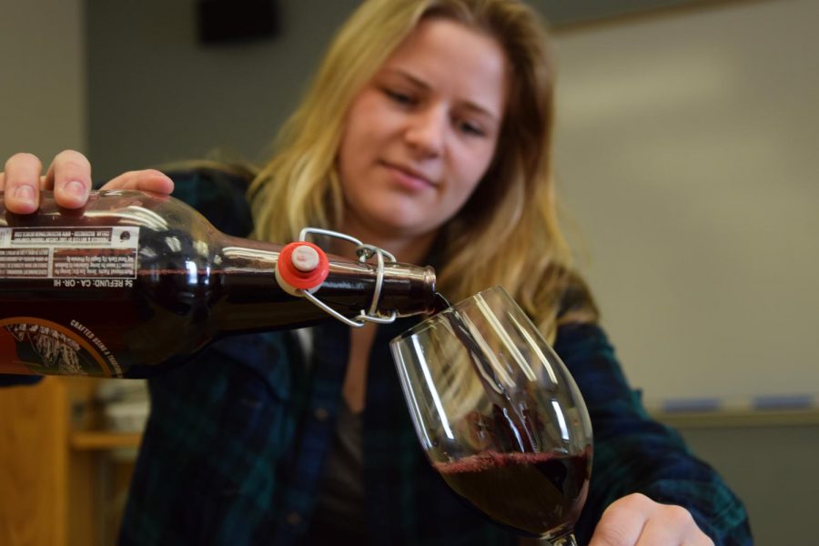 Viticulture and Enology Junior Rebecca Bartelheimer pours a glass of homemade wine and discusses the passing of HB-1563 on Wednesday in Clark Hall.
