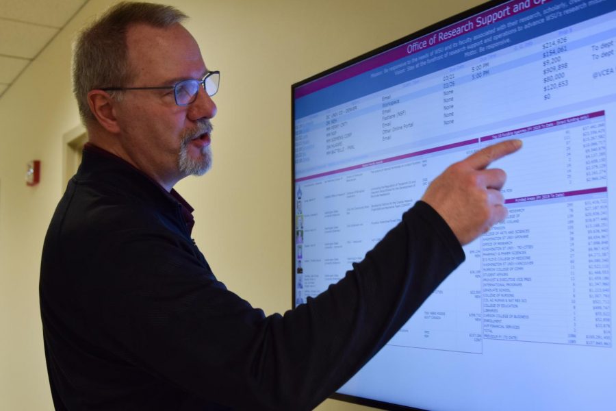 Dan Nordquist, associate vice president of research support and operations at the WSU Office of Research, points at a chart with the top funding donors for WSU.