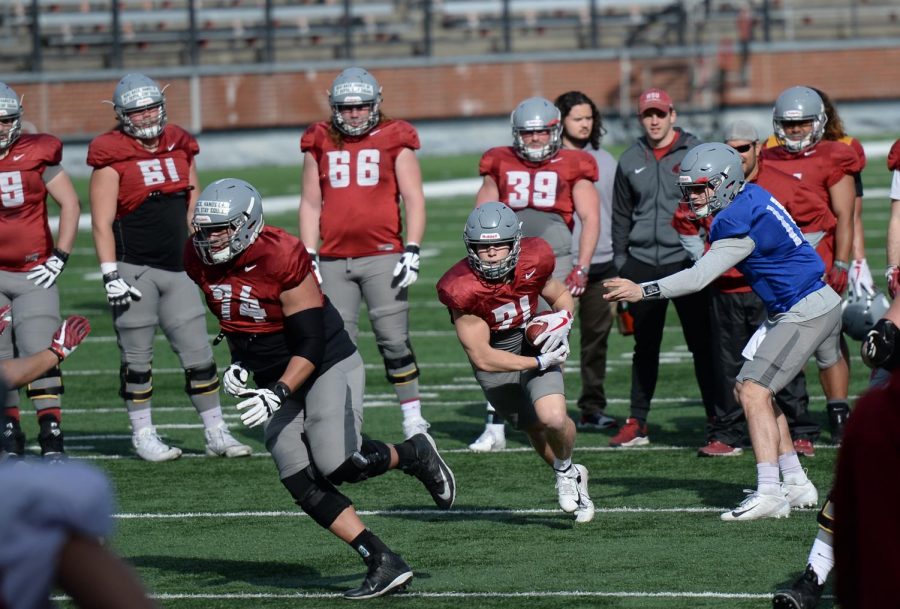 Redshirt sophomore quarterback John Bledsoe, right, hands the ball off to sophomore running back Max Borghi, middle, while senior offensive line Robert Valencia rushes forward to block Tuesday afternoon at Martin Stadium. 