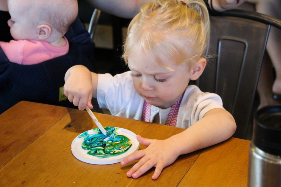 Children make cosmic suncatchers by pouring a white, liquid glue onto a container lid and then swirling in food coloring to create a marble like pattern on Tuesday morning at the Moscow Food Co-op.