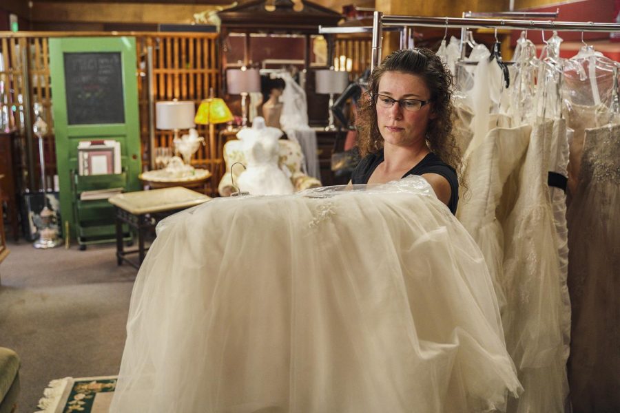 Viktoria Veliz, part-time employee of Lily Bee’s Consignment Shop, shows a wedding dress that was
left to dry in the shop Thursday afternoon following the flood that swept down Main Steet Wednesday.