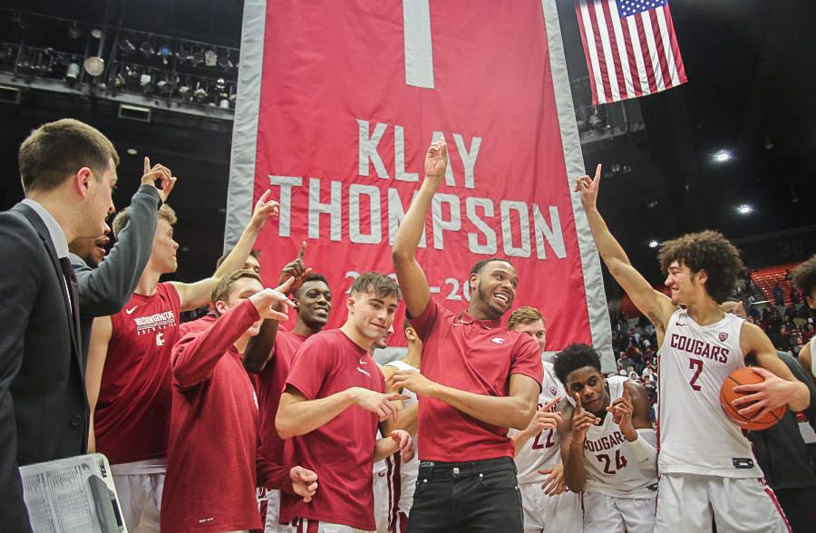 The WSU mens basketball team poses in front of Klay Thompsons banner bearing his now-retired jersey number.