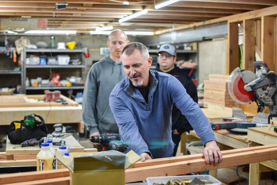 Senior pastor Thad DeBuhr shows volunteers how to build a bunk bed at 6 p.m. Monday in the basement of his Pullman home.